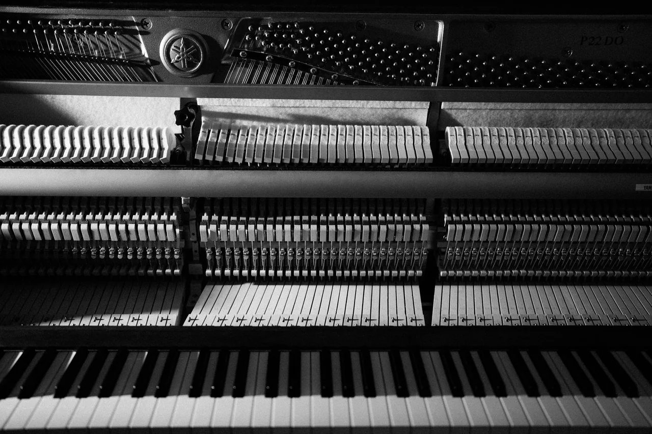 The exposed strings, hammers and keys of an upright piano